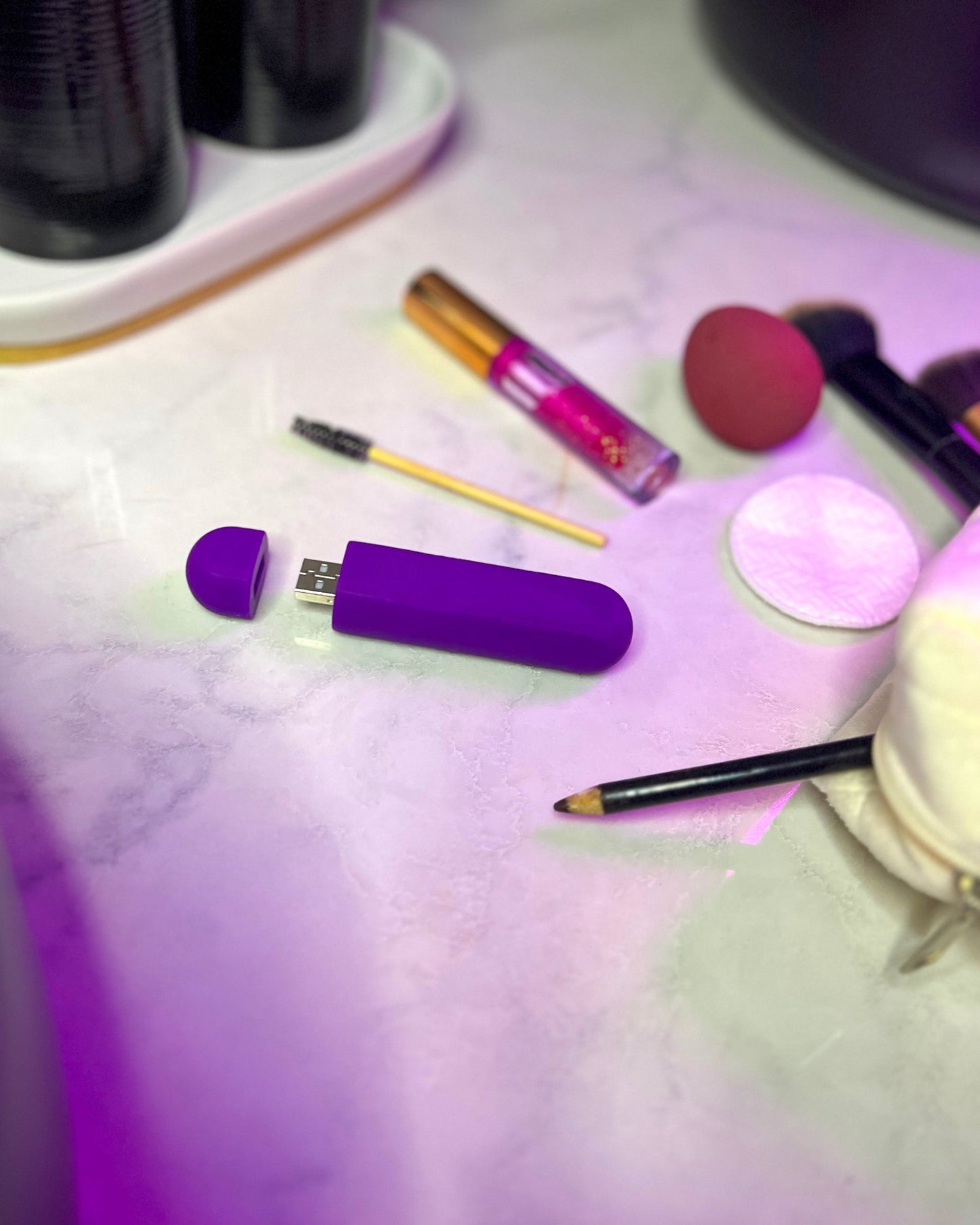 Purple bullet vibrator shown outside a woman's bag with makeup items, highlighting its discreet size and compact design, Come Now