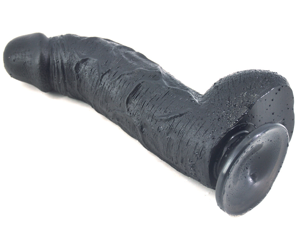 Black FAAK curved dildo left side laying on ground