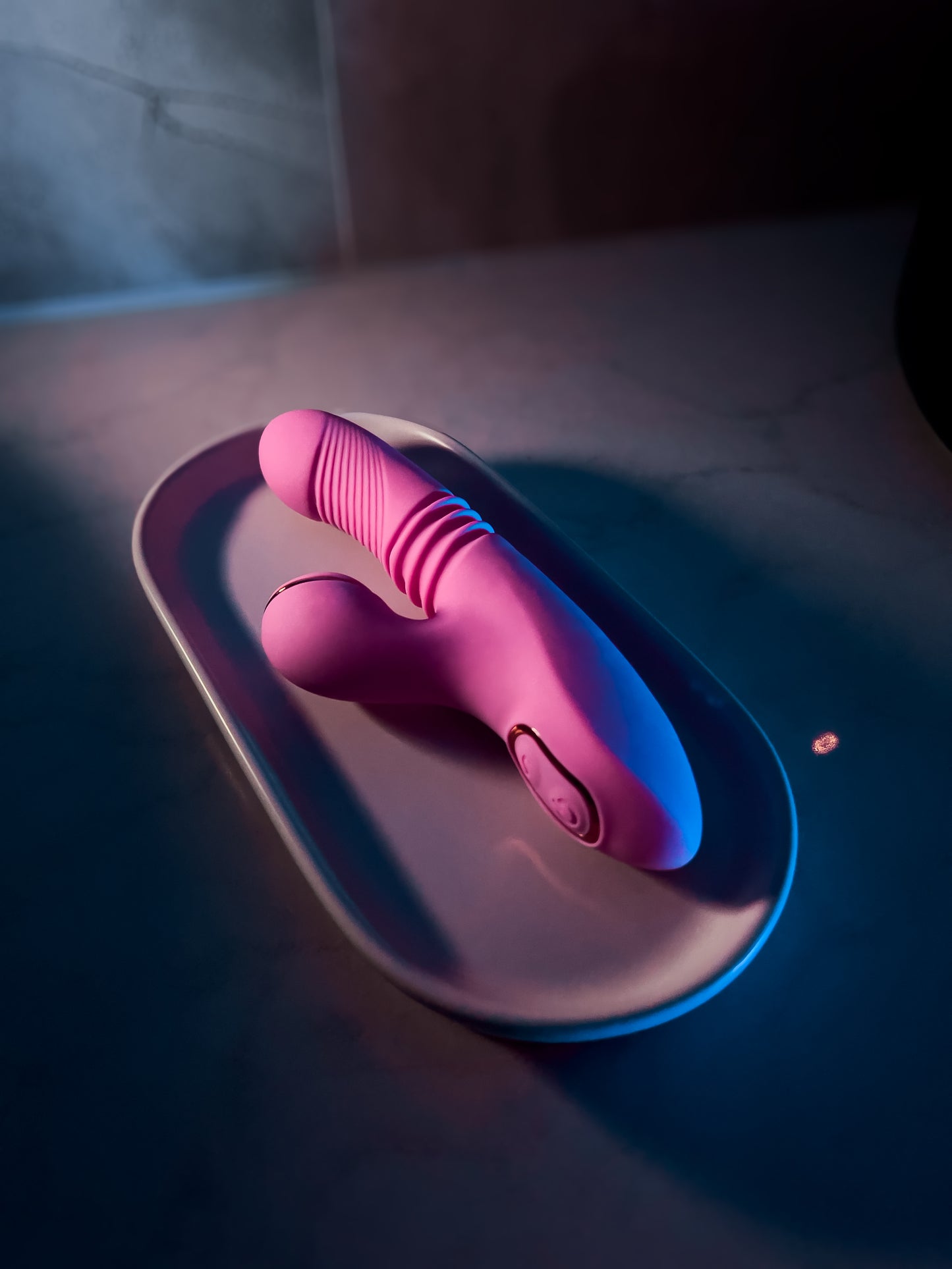 Pink twirling and suction vibrator elegantly placed on a bathroom display plate, emphasizing its luxurious design